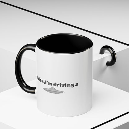 Ceramic coffee mug with "Relax, I’m Driving" UFO design in 11 oz or 15 oz size, featuring a colorful alien and spaceship illustration.