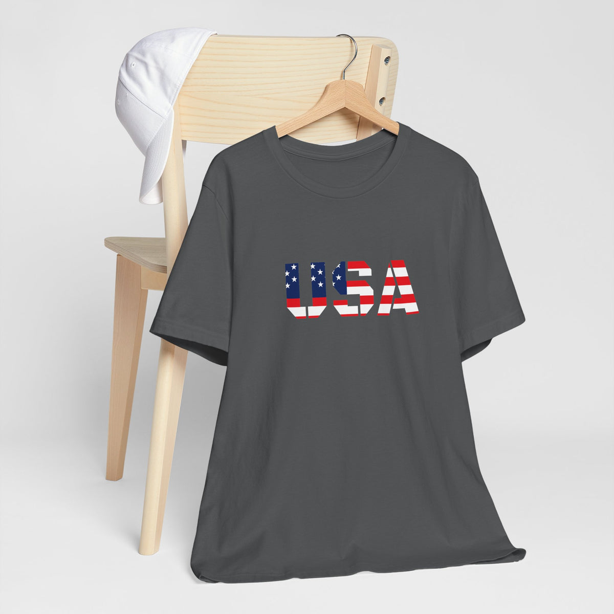 USA flag text T-shirt by Printify featuring patriotic Fourth of July design, denim background, and casual fit.
