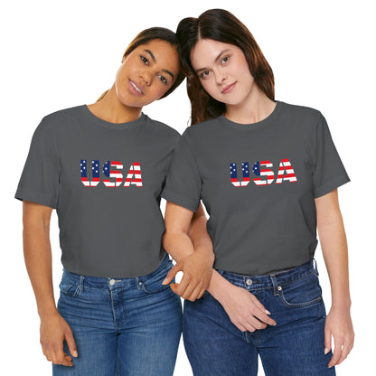USA Flag Text T-Shirt by Printify featuring patriotic red, white, and blue colors and a bold American flag design on the front.