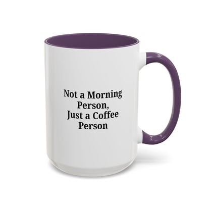 Ceramic coffee mug with "Not a Morning Person, Just a Coffee Person" quote, featuring a white background and colorful text.