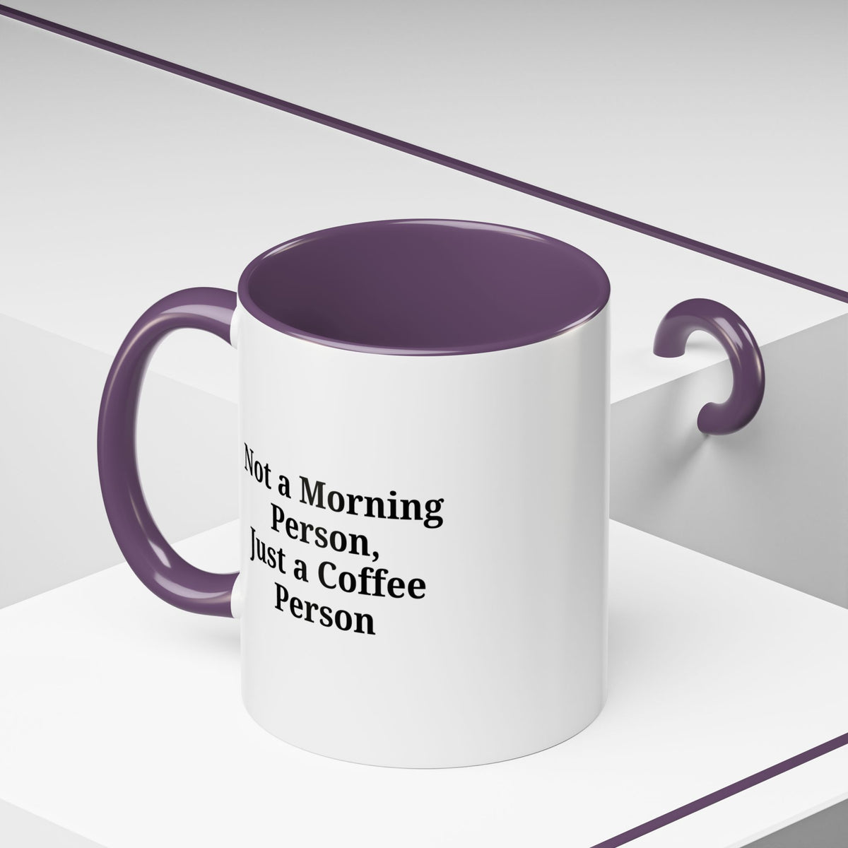 Ceramic coffee mug with "Not a Morning Person, Just a Coffee Person" slogan, featuring a white background and colorful lettering.