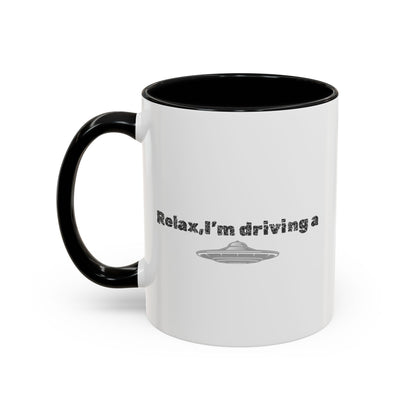Ceramic coffee mug with "Relax, I’m Driving" UFO design, available in 11 or 15 oz, by Printify, shown with a playful alien motif.