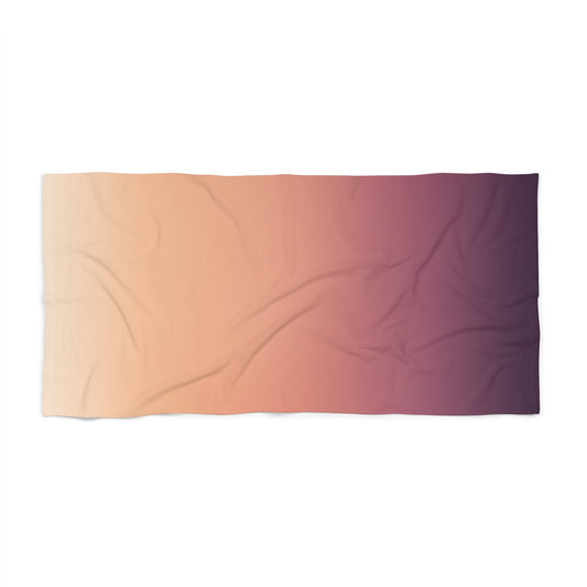 Sunset ombre beach towel by Printify featuring a pink to purple gradient design, spread out on a sandy beach.