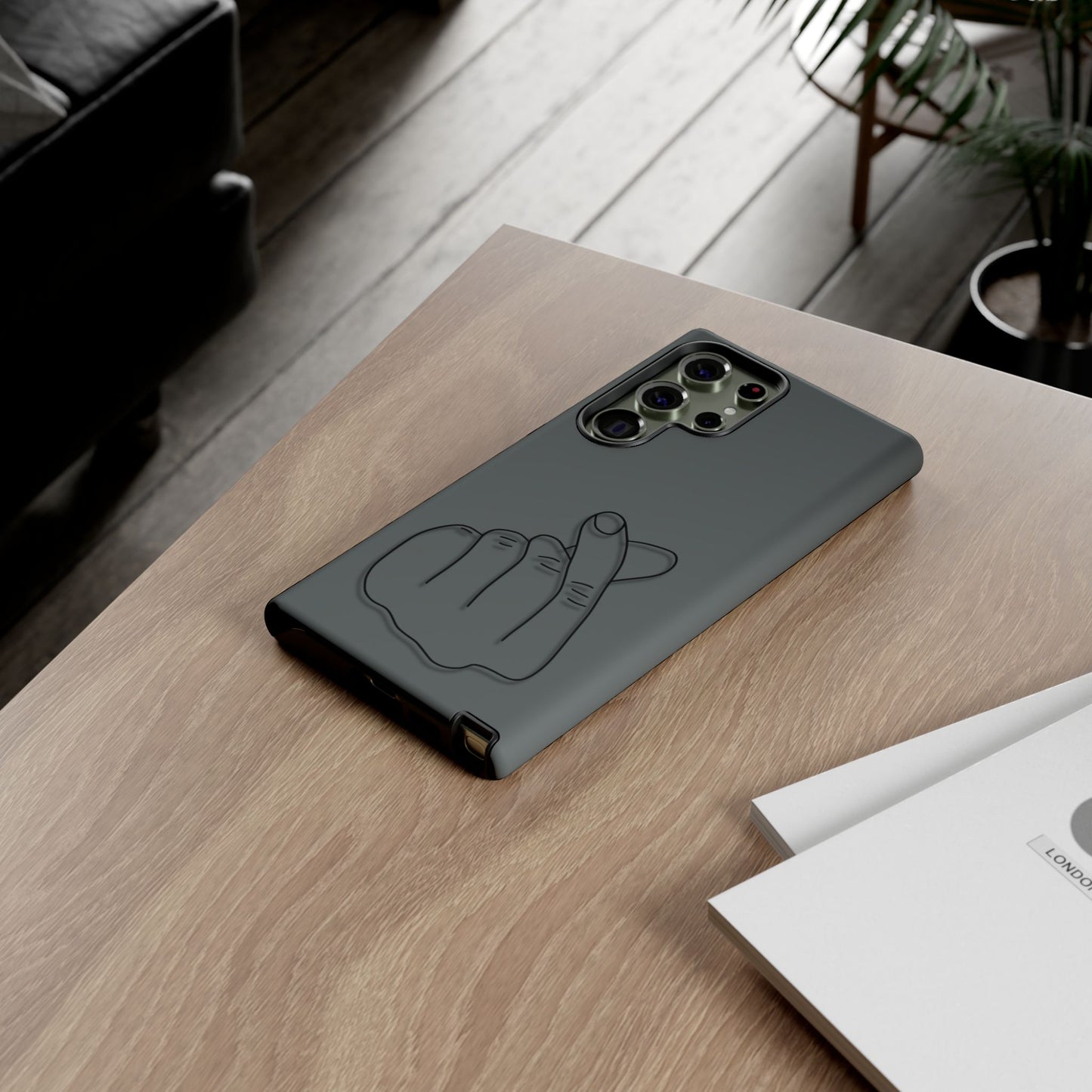 Silicone phone case with embossed Korean finger heart design in black, featuring a slim protective cover from Printify.