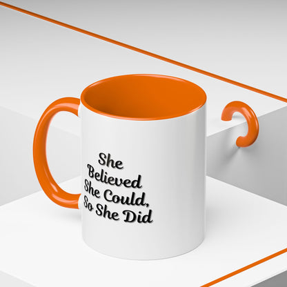 White ceramic motivational coffee mug with black text saying "She Believed She Could, So She Did" on a plain background.
