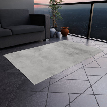 Modern gray outdoor rug by Printify, durable indoor-outdoor flooring for patios and decks, shown laid out on a patio surface.