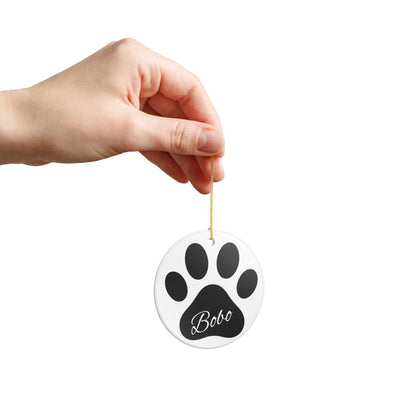 Black paw print ceramic ornament with pet's name, perfect for pet memorial Christmas decoration by Printify.