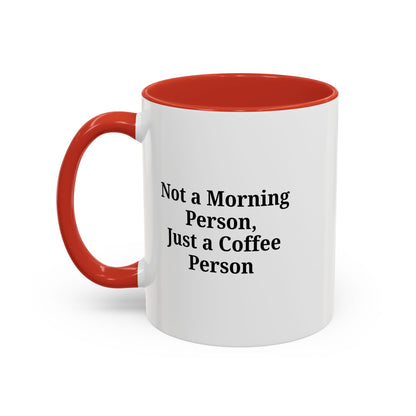 Ceramic coffee mug with "Not a Morning Person, Just a Coffee Person" quote, featuring a white background and colorful text.