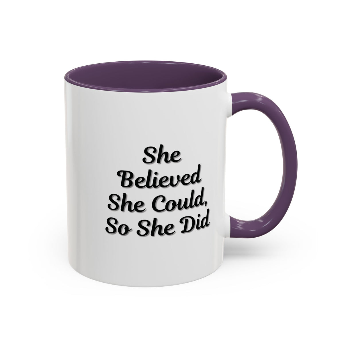 White ceramic motivational coffee mug with black text "She Believed She Could, So She Did" by Printify, shown on a wooden surface.