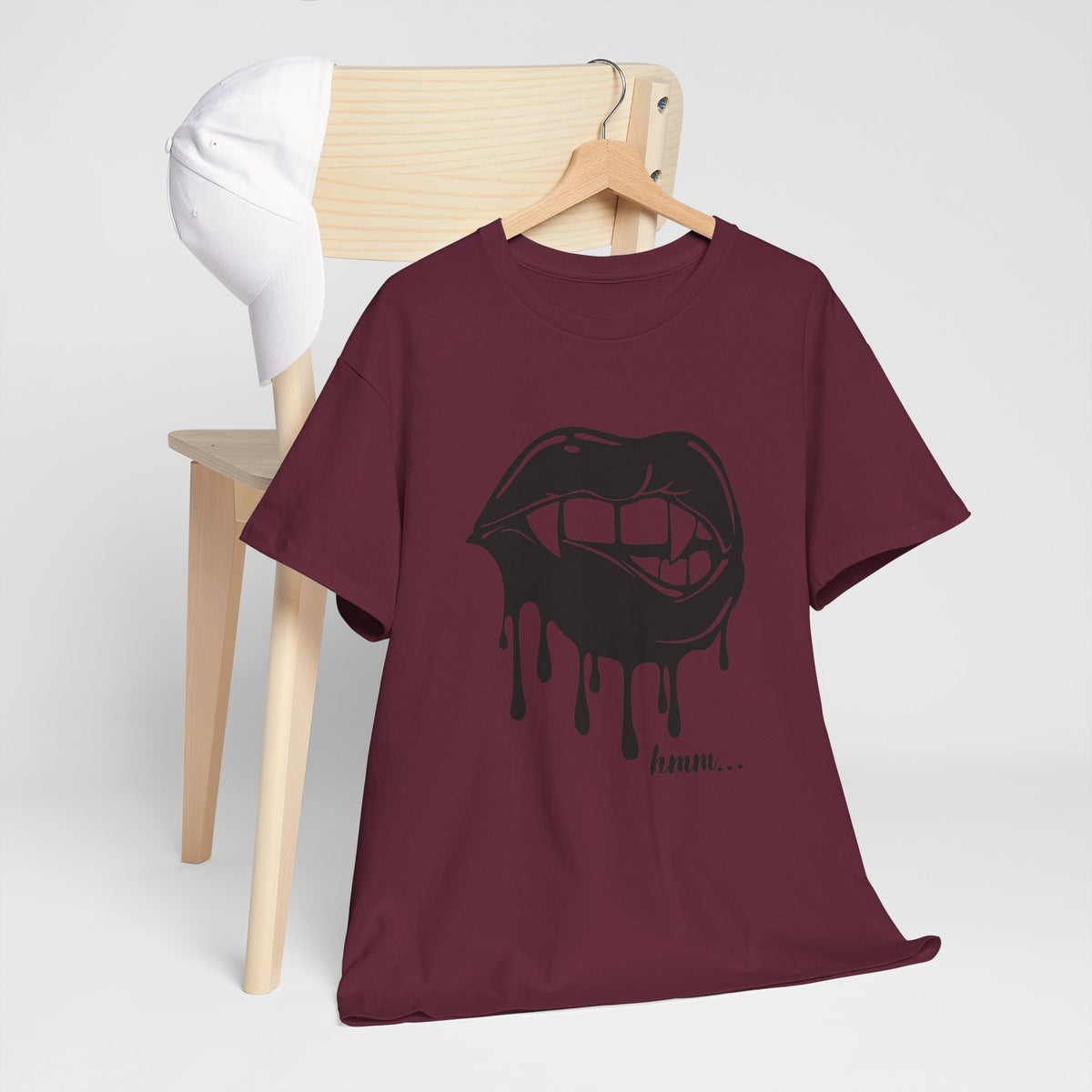 Black graphic T-shirt featuring a dripping lips 'hmm...' bite design from Printify, with bold and colorful illustration on front.