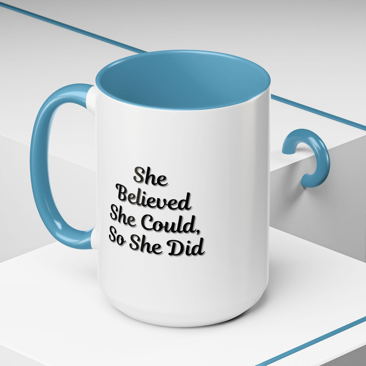 White ceramic motivational coffee mug with black text that reads "She Believed She Could, So She Did" on a plain background.