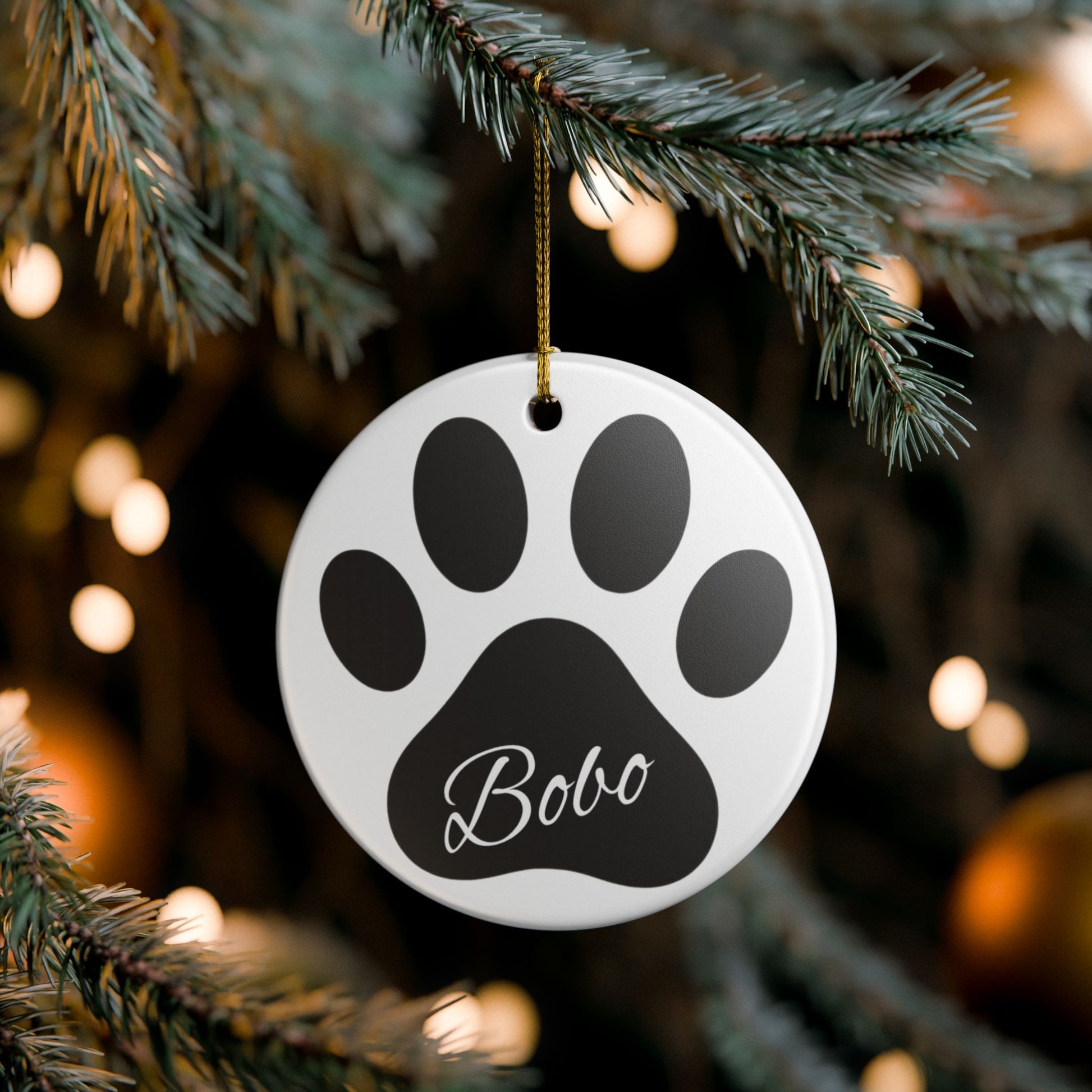 Black paw print ceramic ornament with pet's name, perfect for memorial Christmas decoration, by Printify.