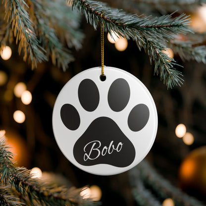 Black paw print ceramic ornament with pet's name, perfect for memorial Christmas decoration, by Printify.
