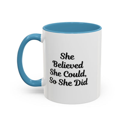 White ceramic motivational coffee mug with black text reading "She Believed She Could, So She Did" on a plain background.