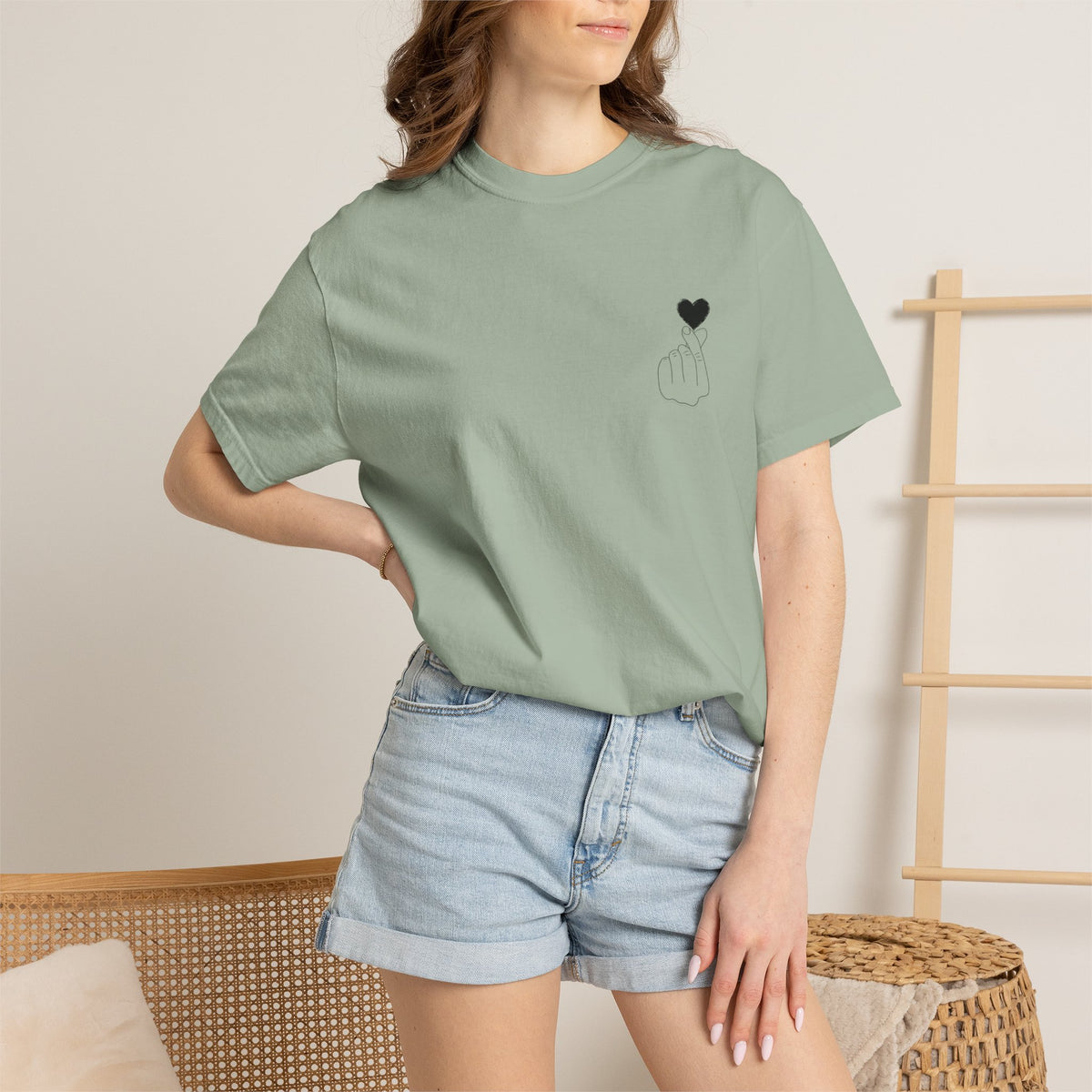Black T-shirt with a minimalist white finger heart graphic, designed by Printify, featuring a simple, stylish heart illustration.