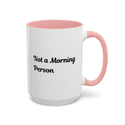 Ceramic coffee mug with "Not a Morning Person" print, 11oz or 15oz size, from Printify, shown with a cozy coffee setting.
