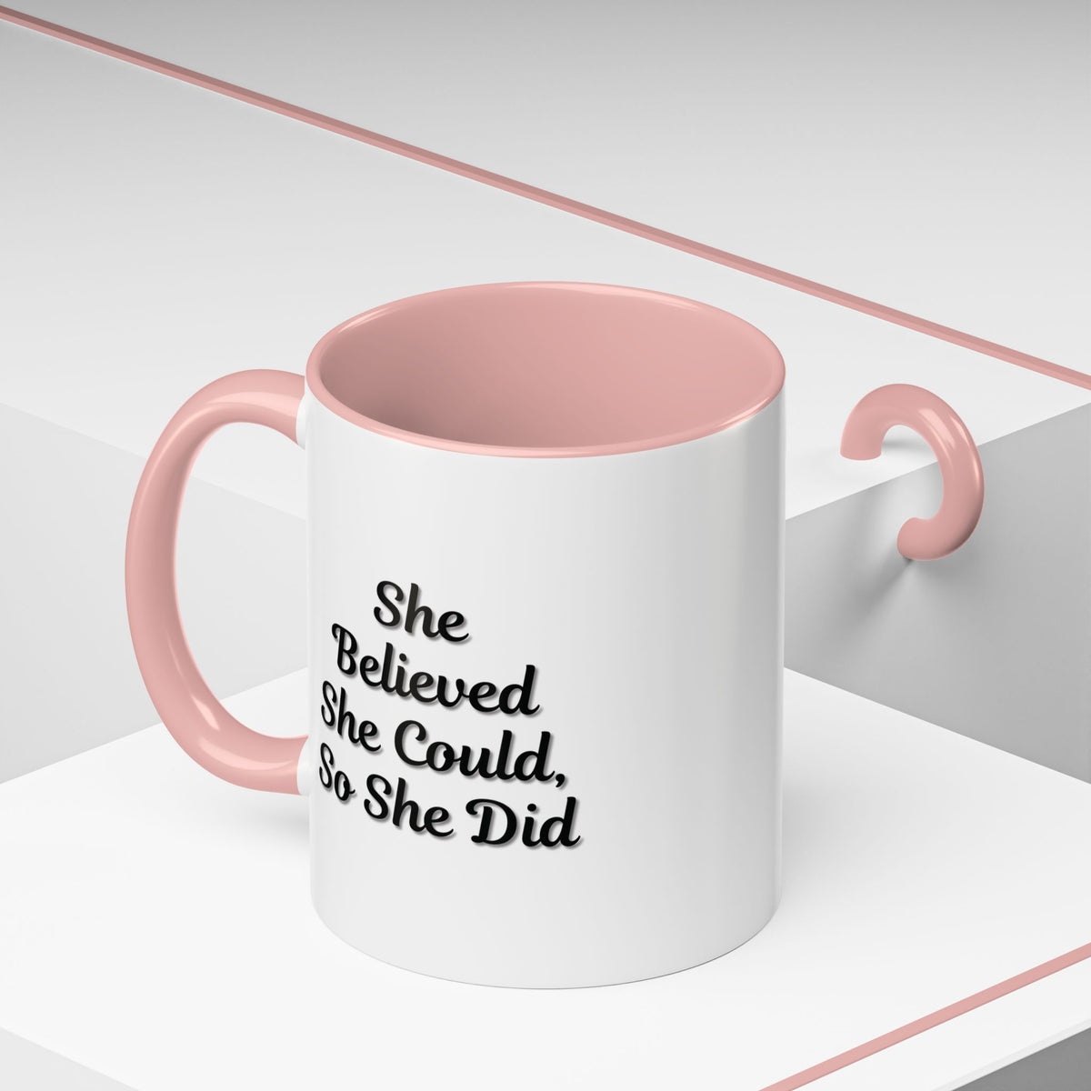 White ceramic motivational coffee mug with "She Believed She Could, So She Did" quote in black text, designed by Printify.