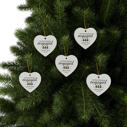 Ceramic "Our First Christmas" engaged heart ornament with red ribbon, featuring festive holiday design and Printify branding.