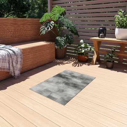 Gray outdoor waterproof rug for patio and deck, shown as a modern blanket-style mat with textured fabric surface.