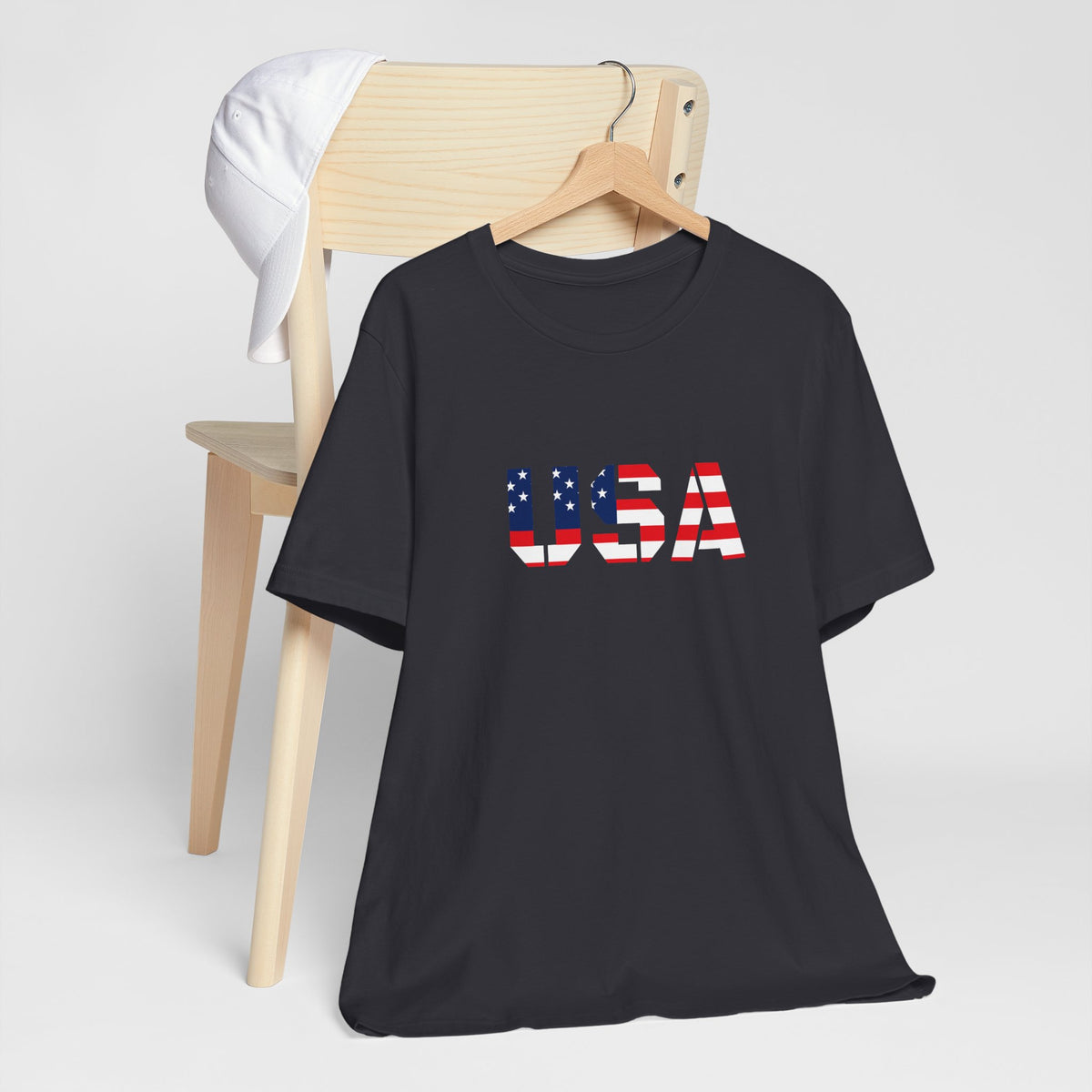 USA flag text T-shirt by Printify featuring patriotic design for Fourth of July, casual wear with bold red, white, and blue colors.