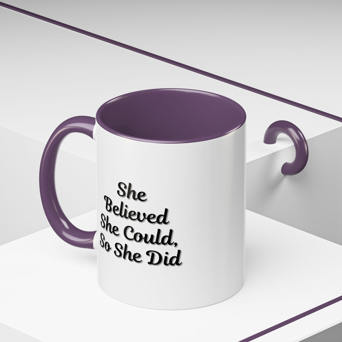 White ceramic motivational coffee mug with black text reading "She Believed She Could, So She Did" displayed on a plain background
