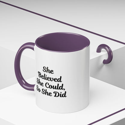 White ceramic motivational coffee mug with black text reading "She Believed She Could, So She Did" displayed on a plain background